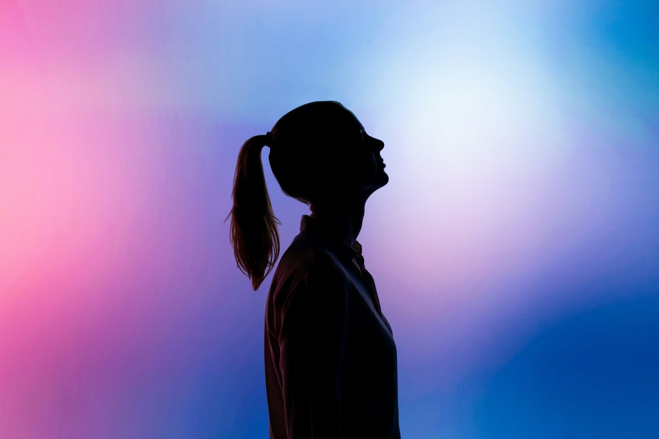 Silhouette of a person in profile against a graded pink and blue background